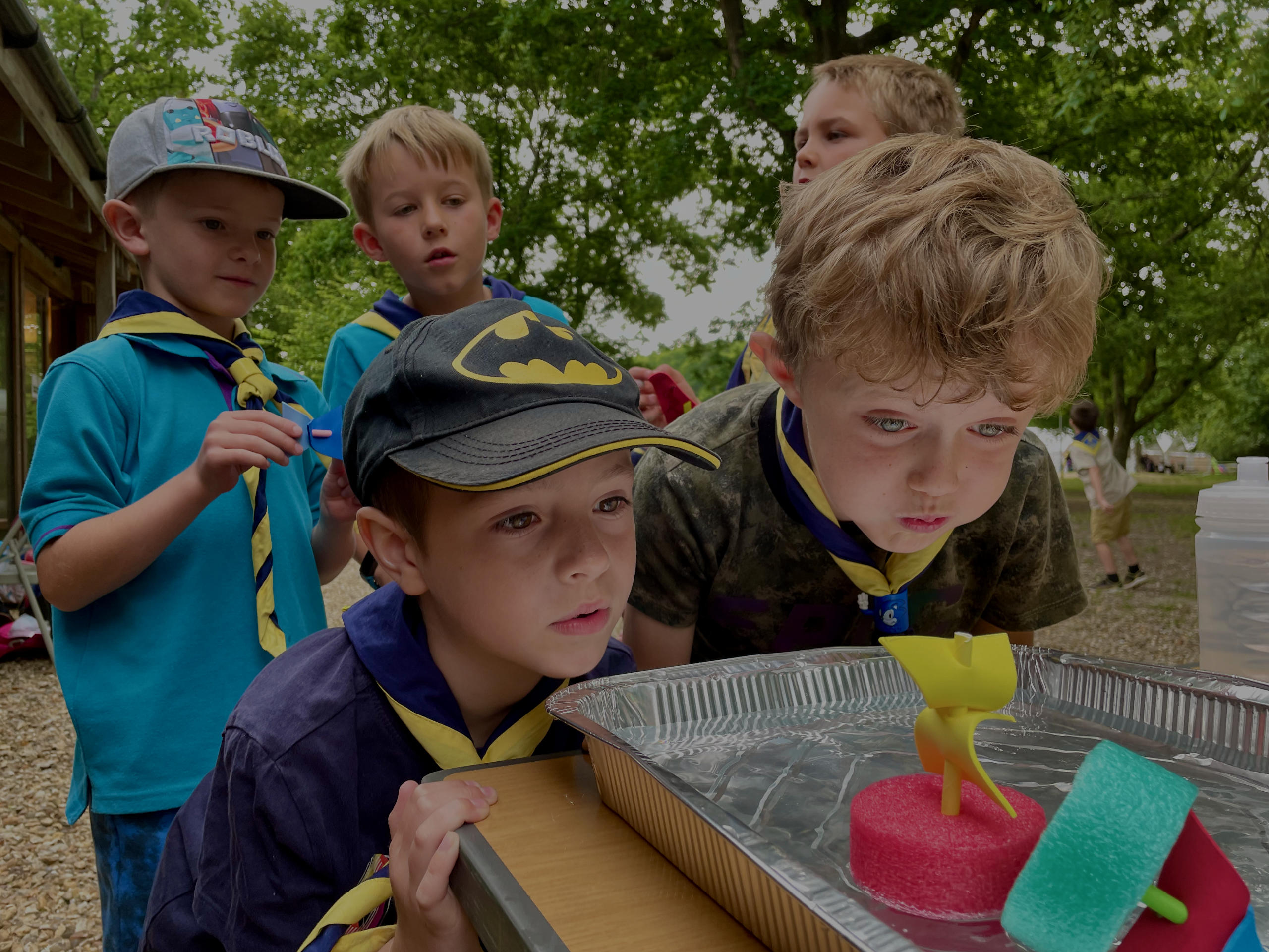 Beaver Scouts blowing boats made from a pool float across a tray of water